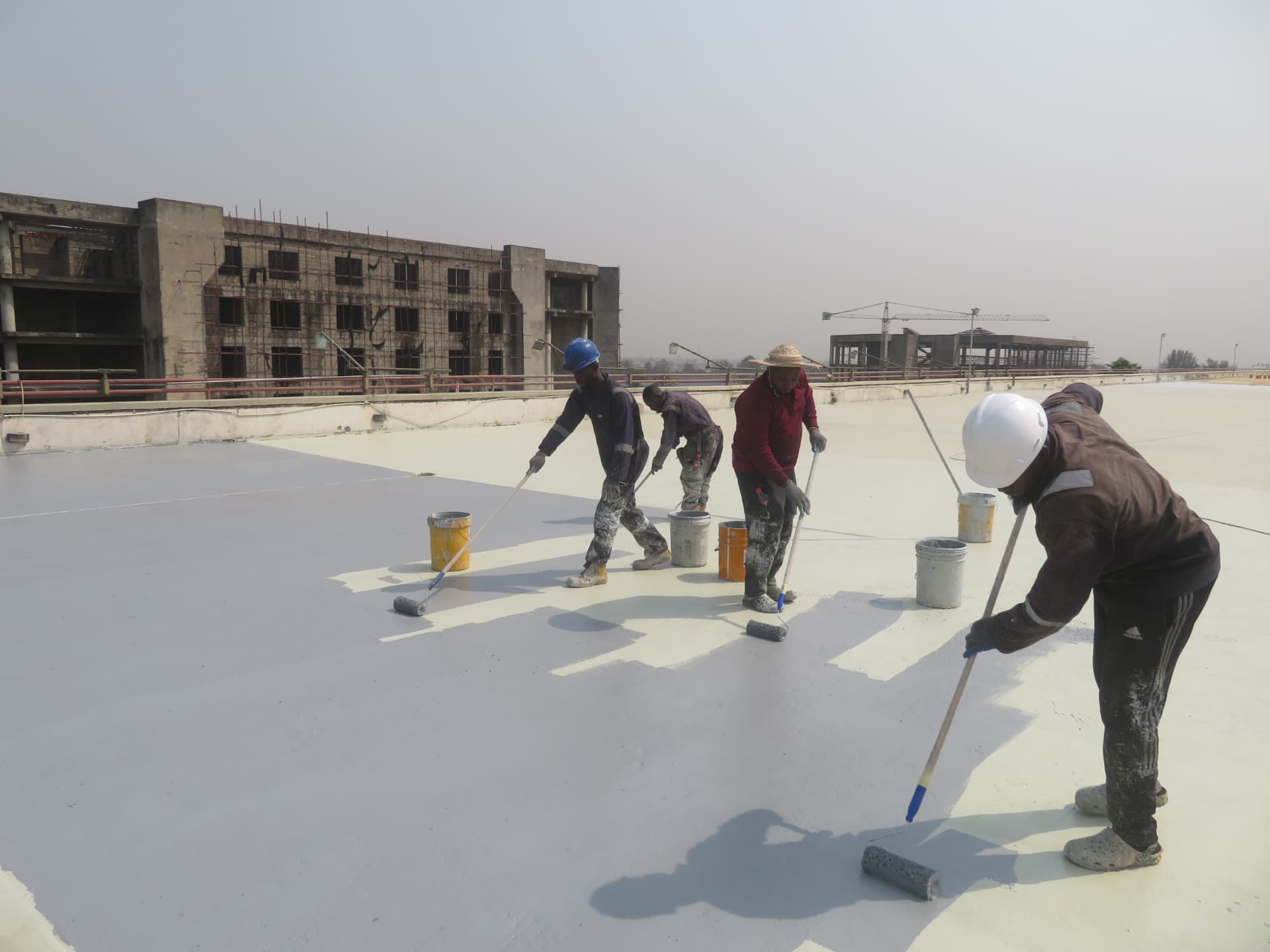 Imperial Works crew roller-applying waterproof coating to a rooftop